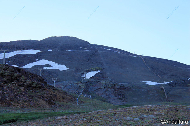 Paravientos, remontes y pistas de esquí y Veleta al fondo en una ruta de Senderismo por la Estación de Esquí Sierra Nevada