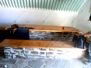 Interior - mesas y bancos - en el Refugio-Vivac de la Caldera