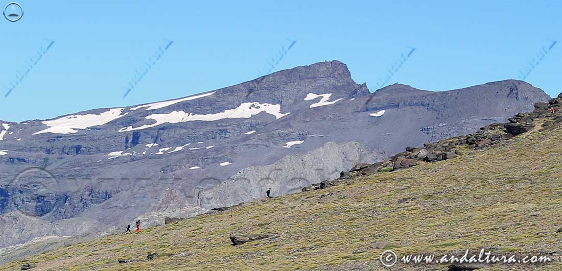 Senderistas ascendiendo al Mulhacén, al fondo el Veleta y el Cerro de los Machos