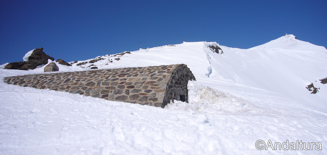 Refugio-vivac de la Carihuela, cubierto de nieve, y el Veleta