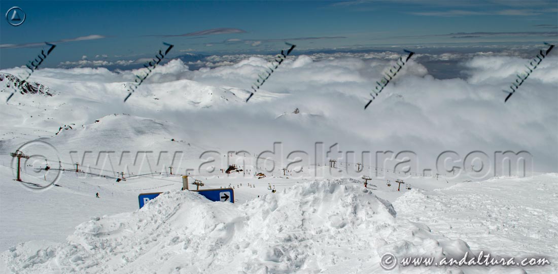 Cartel tapado por la nieve en la Estación de Sierra Nevada mientras van ascendiendo las nubes